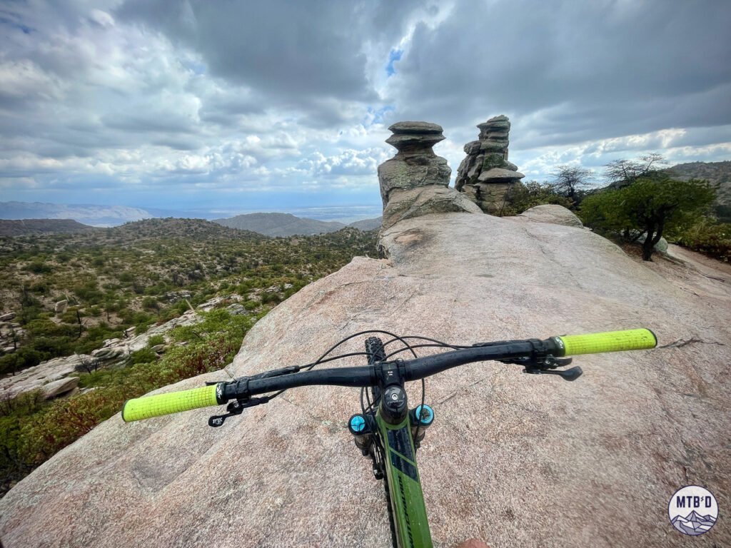 A view of mountain bike handlebars at granite outcrop overlook on Bug Springs Trail with views toward Gordon Hirabayashi Recreation Site Mt. Lemmon Tucson Arizona