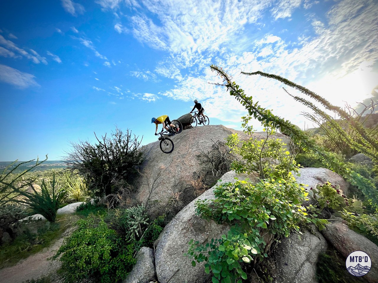 Two mountain bikers sending a steep rock roll on Gem Trail at Golder Ranch, Tucson Arizona