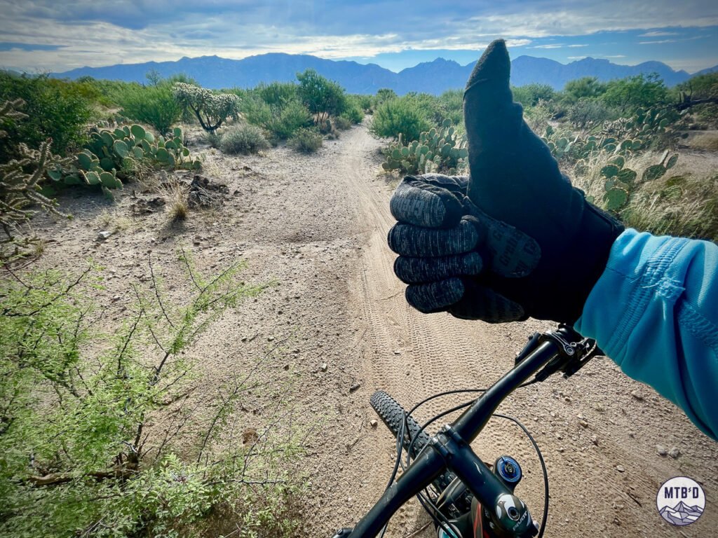 Gloved hand giving thumbs up on Honeybee Rail X Ranch singletrack, Tucson Arizona