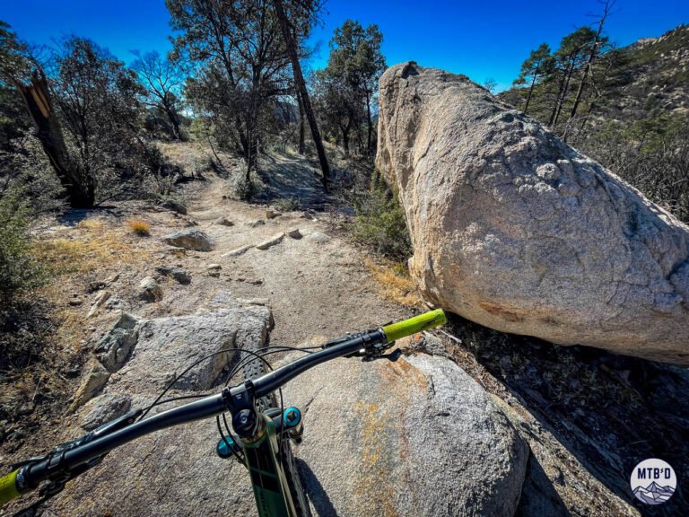 Mountain bike handlebars over singletrack trail with massive granite boulder on Mt. Lemmon, Santa Catalina Mountains Tucson Arizona