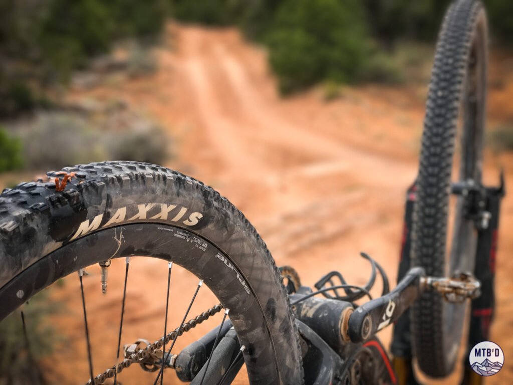 Mountain bike flipped upside down for tubeless tire repair with bacon strip on Porcupine Rim trail, Moab Utah